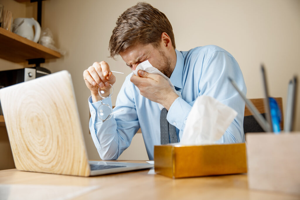 sick man with handkerchief sneezing blowing nose while working office businessman caught cold seasonal flu