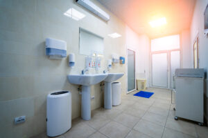 Clean public hospital bathroom with handrail soap and paper towel dispenser